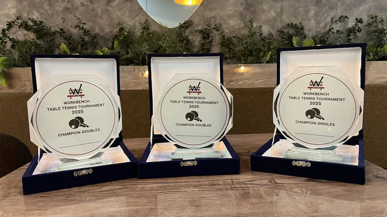 Three WorkBench Table Tennis Tournament 2025 champion plaques in open cases