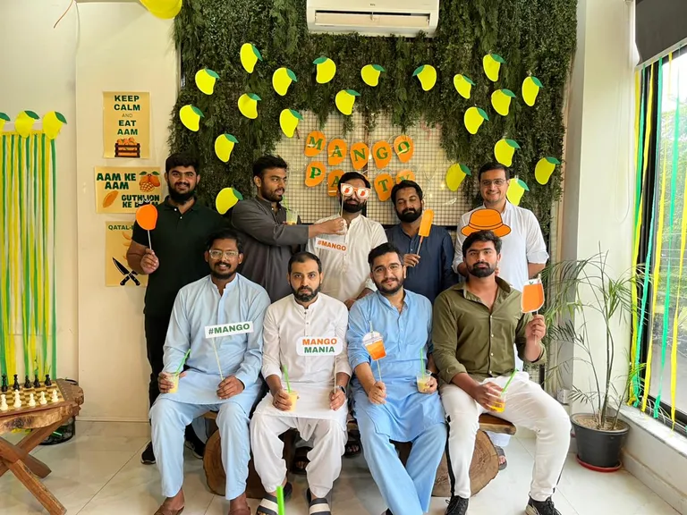 Members posing with mango props and drinks at the Mango Party photo booth