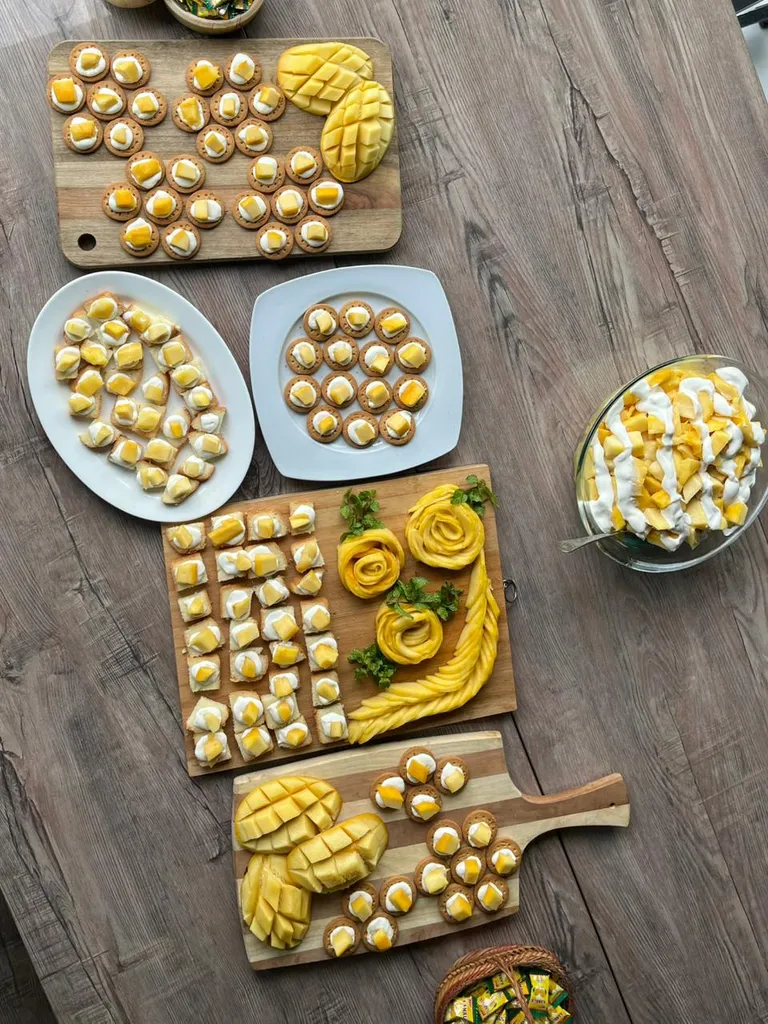 A table spread of mango desserts and canapes on wooden boards