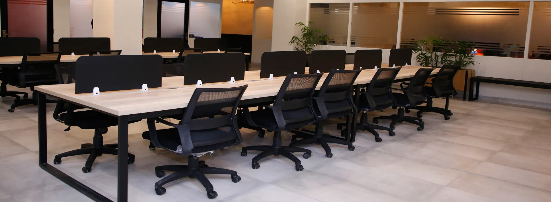 A long run of shared desks and ergonomic chairs on the open floor