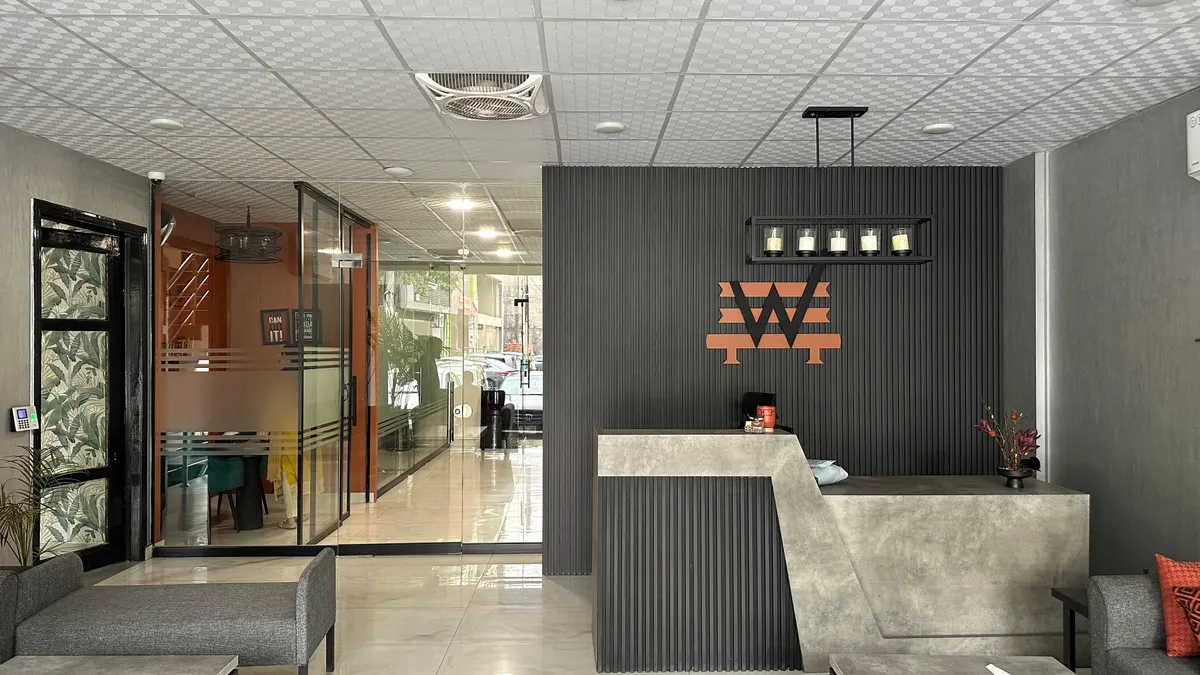 WorkBench reception in Lahore, with the amber W mounted on a charcoal fluted wall above a concrete desk.