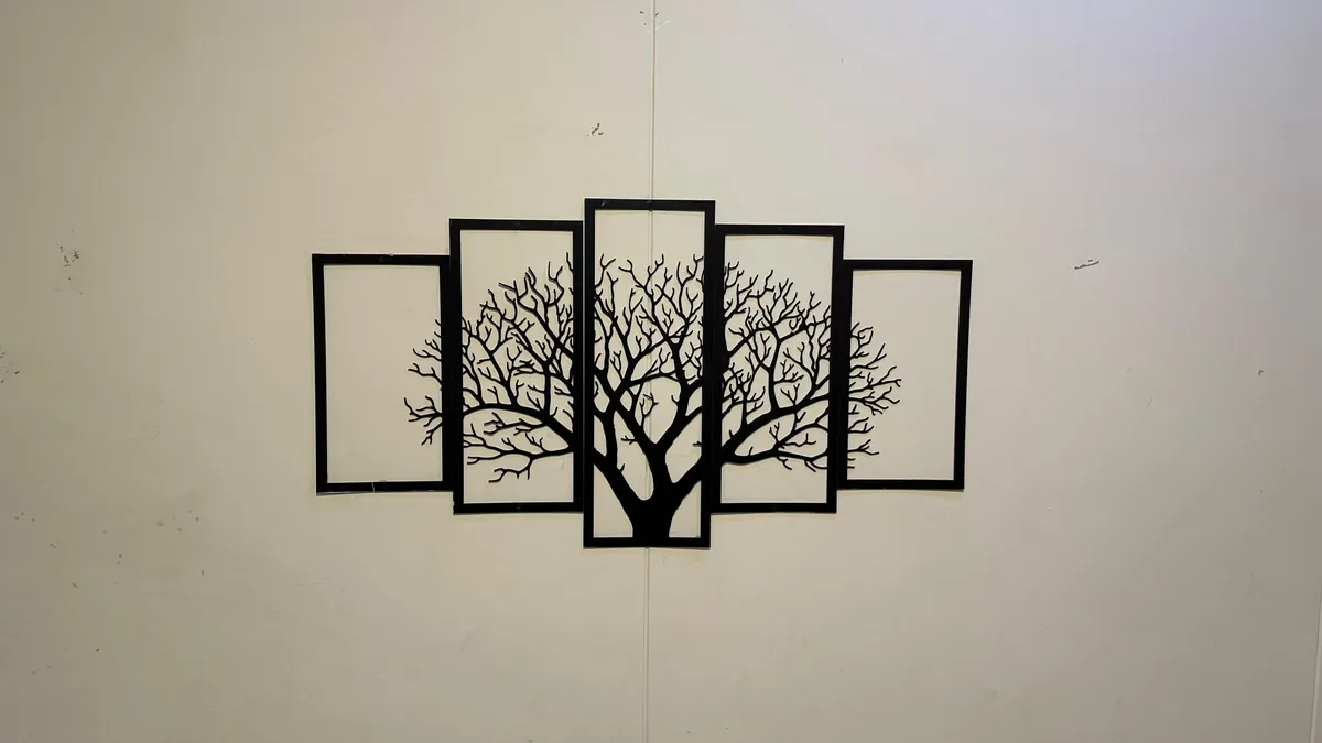 A black steel tree sculpture in five panels mounted on a plain painted wall inside WorkBench.